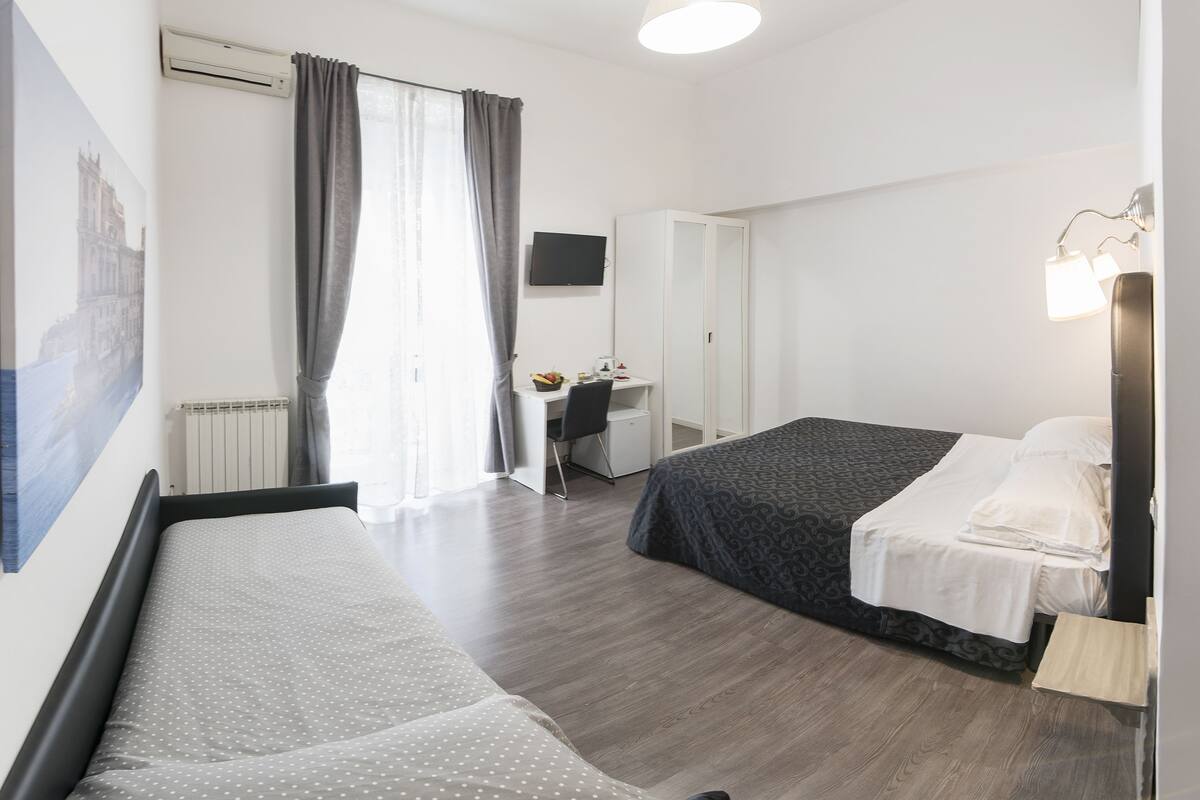 A hotel room with a bed, a desk, and a chair.