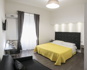 A hotel room with a bed, a desk, a chair, a sofa, and a window with curtains. - B&B Solimena (Naples)