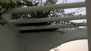 Ein Bogenportal führt zu einer Straße mit Blick auf ferne Hügel.