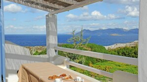 Ein Balkon mit Frühstückstisch mit Blick auf eine malerische Küstenlandschaft.