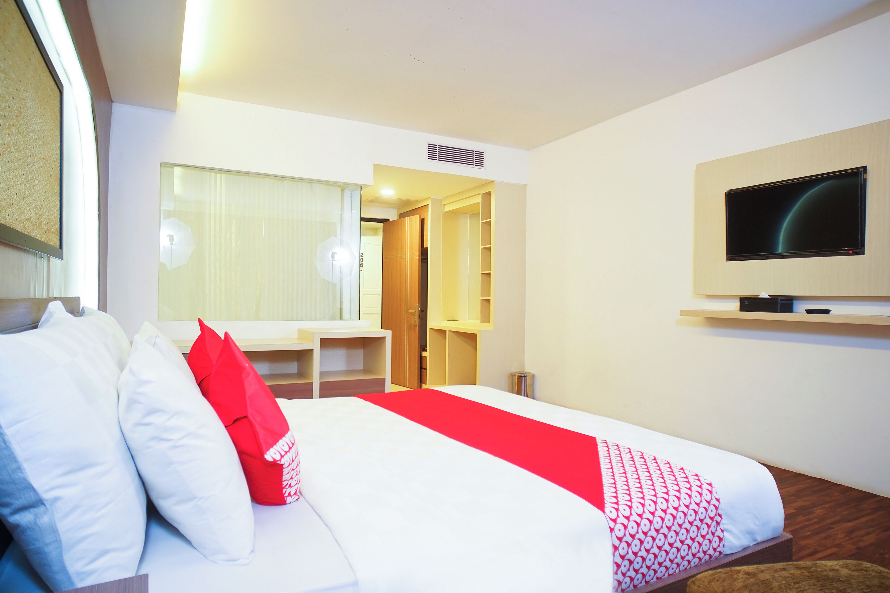 Une chambre d’hôtel équipée d’un lit, d’un bureau, d’une télévision et d’une armoire.