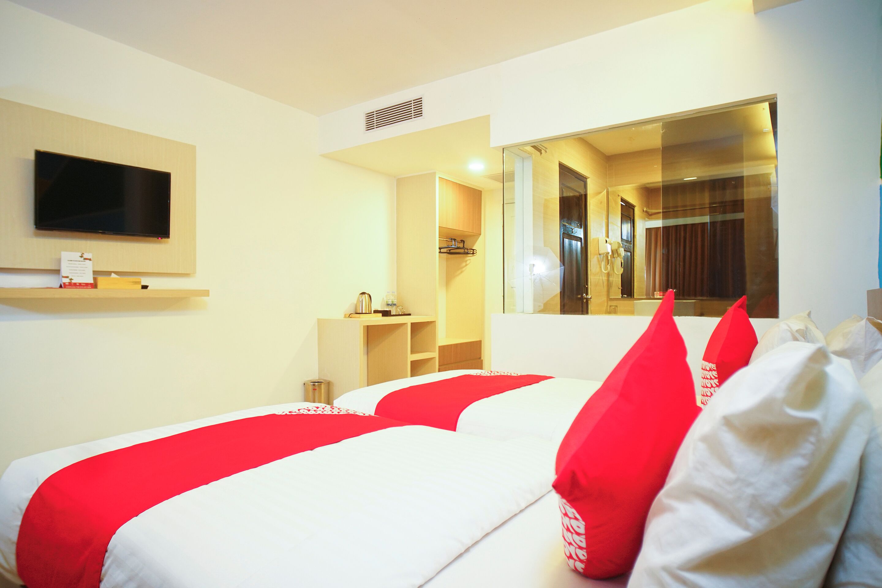 Een hotelkamer met twee bedden, een televisie, een spiegel en een kleine kitchenette.