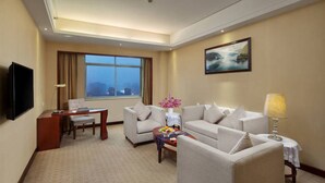 A hotel room with a large window, a flat-screen TV, a sofa, a coffee table, and a lamp. - Yiyang Huatian Hotel (Yiyang)