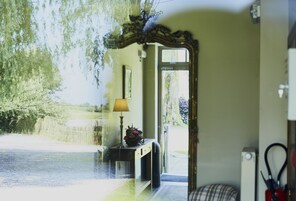 Una habitación con un espejo grande, una lámpara y vistas a un jardín.