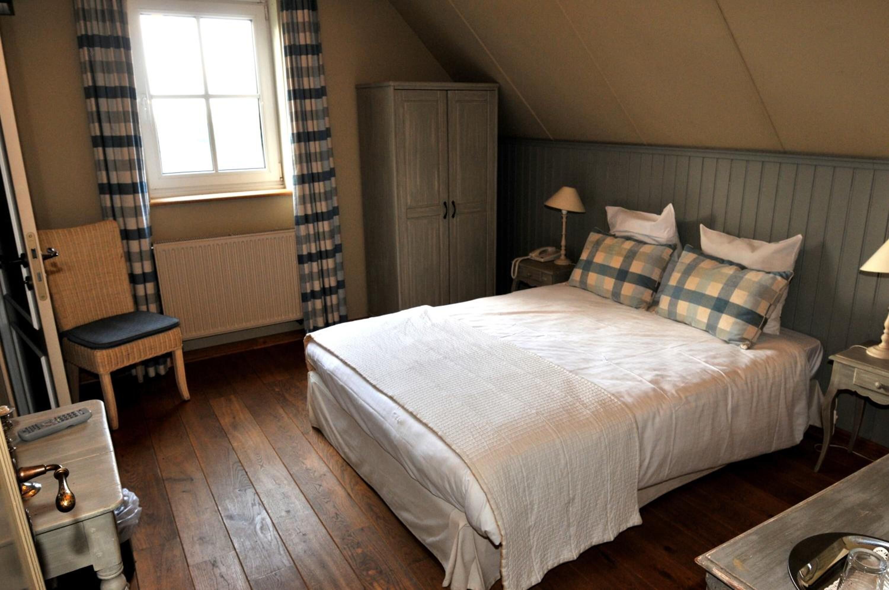 A bedroom with a large bed, a chair, a wardrobe, and a radiator.