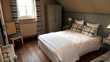 A bedroom with a large bed, a chair, a wardrobe, and a radiator.