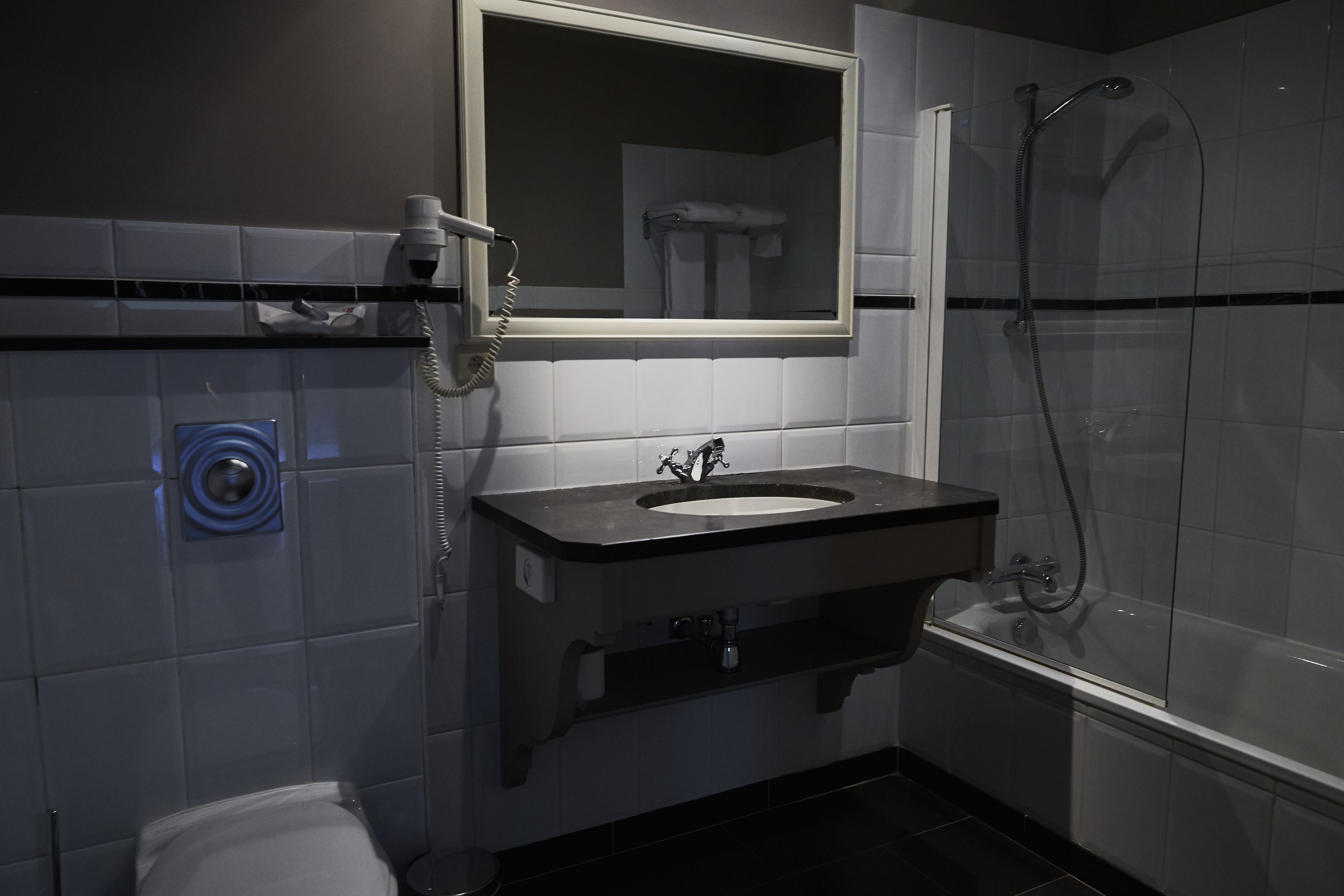 Un baño moderno con lavamanos, espejo y ducha.