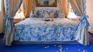 A four-poster canopy bed with floral bedding, a mirror above the bed, and curtains tied at the corners. - Landgasthof Alte Bergmühle (Dreieich)
