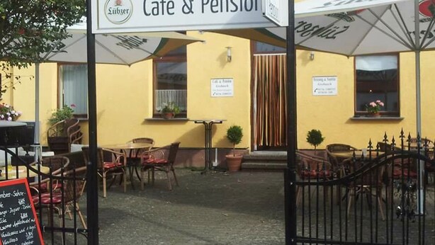 Café y pensión con terraza, un cartel y una pizarra con el menú.