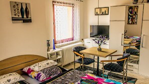 Un dormitorio con cama, escritorio, silla, radiador y televisor.