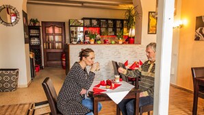 Un comedor con una mesa dispuesta para dos, una cocina al fondo y una sala de estar con un sofá y una mesita de centro.
