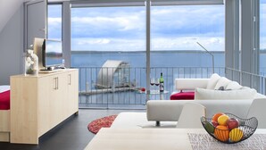 Un salon moderne doté d’un grand balcon, d’un coin repas et offrant une vue sur l’eau.