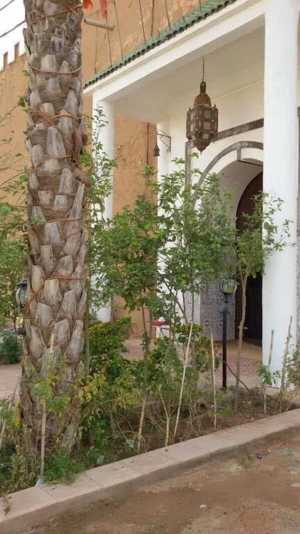 Uma entrada de edifício com um pilar de pedra, um portão de metal e um candeeiro.