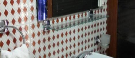 A bathroom with a white sink, a mirror, and a patterned wall.