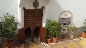 A courtyard with a patterned floor, a central fountain, and potted plants. - Riad Freija (Freyja)