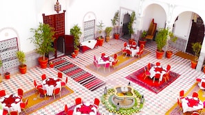 A courtyard with multiple dining areas, potted plants, and a central fountain. - Riad Freija (Freyja)