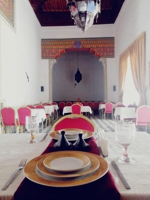 A dining area with tables set for a meal, chairs, and a chandelier. - Riad Freija (Freyja)