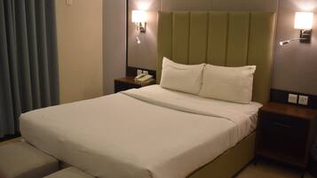 Habitación de hotel con una cama grande, dos mesitas de noche, un teléfono y dos lámparas de pared.