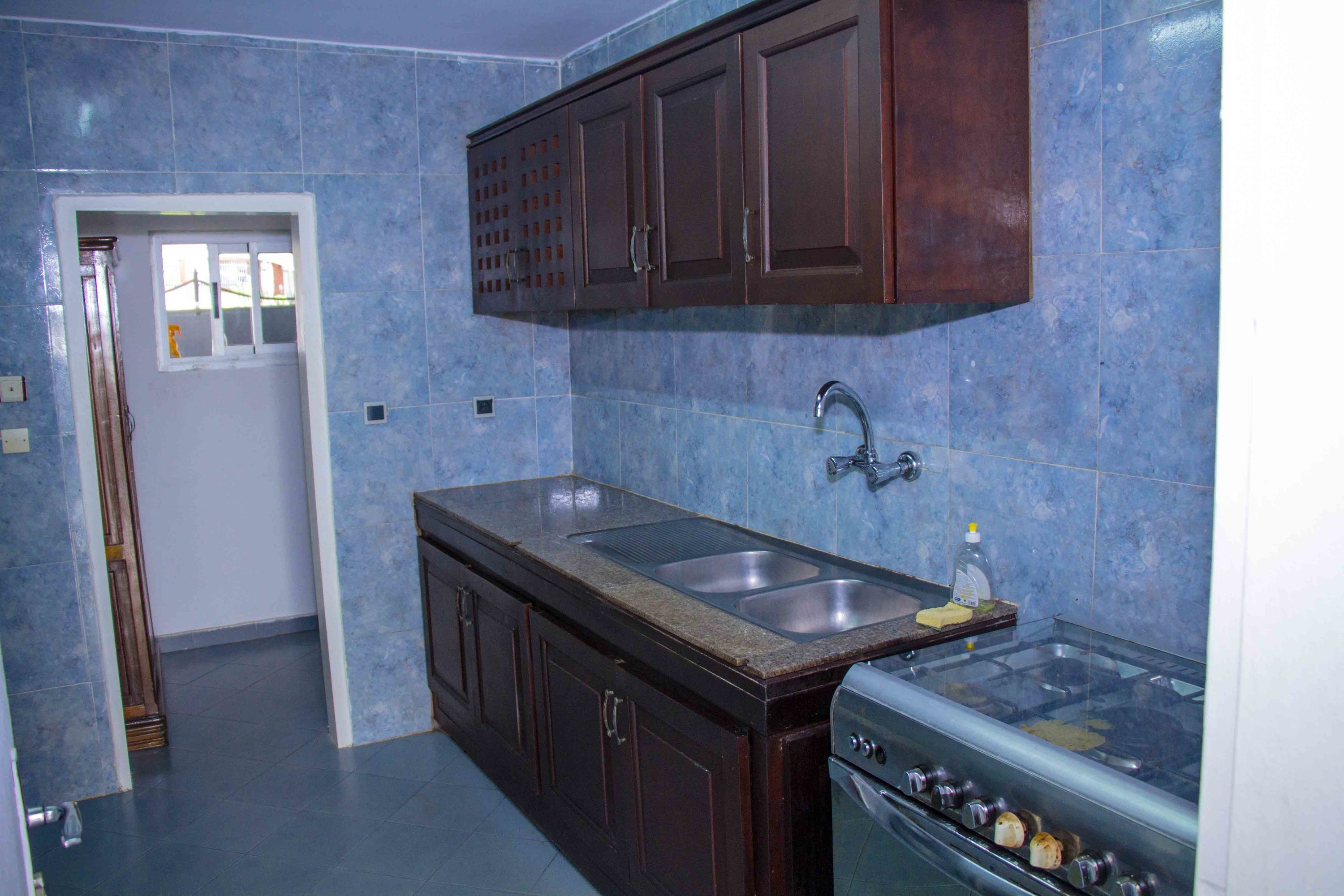 Una cocina con armarios de madera oscura, un lavamanos doble y un horno empotrado.