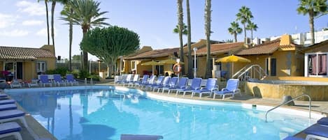 A swimming pool with lounge chairs and palm trees.