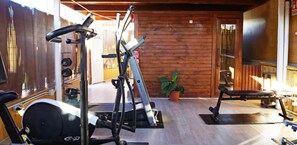 Une salle de sport équipée de matériel d’exercice, avec un mur en bois et une plante en pot.
