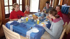 A group of people seated around a table with breakfast items, including plates, cups, and a basket of bread. - Hotel Silverfalls (Nuwara Eliya)