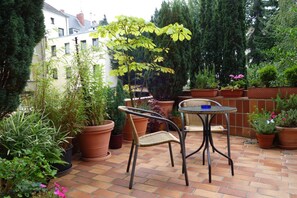 A patio with a table and chairs, surrounded by potted plants and a brick floor. - Pension am Helenenwall (Cologne)