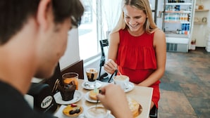 A person in a red dress sitting at a table with a beverage and pastries.