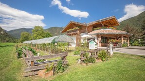 Een houten gebouw met een balkon en een overdekt terras, omgeven door een tuin met een houten omheining.