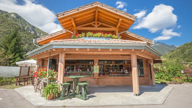 Een houten chalet met pannendak, een overdekt terras en uitzicht op de bergen.
