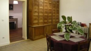 Ein Essbereich mit einem Holzschrank, einem Tisch mit Tischdecke, Stühlen und einem Blumentopf.
