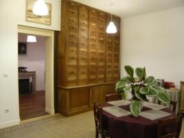 Un comedor con un armario de madera, una mesa con mantel, sillas y una planta en maceta.