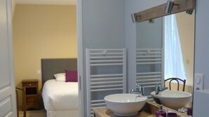 Ein Hotelbad mit zwei Waschbecken, einem Spiegel und einem Holzbadezimmerschrank.