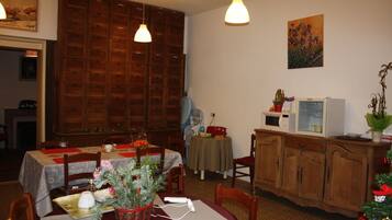 A dining area with a wooden cabinet, a table with a red tablecloth, and a Christmas tree.