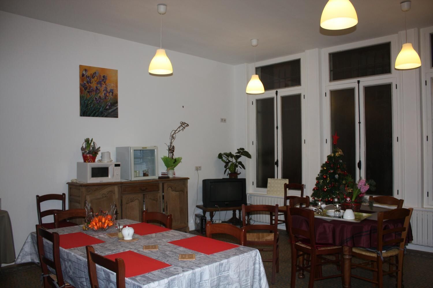 A dining area with a table set for four, a television, and a Christmas tree.