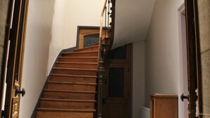 Eine Holztreppe, die zu einer oberen Etage führt, mit einer Tür oben und einem Heizkörper im unteren Bereich.