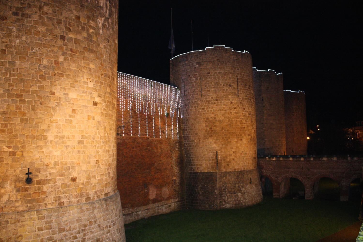 Un mur de pierre ancien, doté d’une tour circulaire et d’un pont.