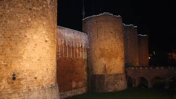 Un mur de pierre ancien, doté d’une tour circulaire et d’un pont.