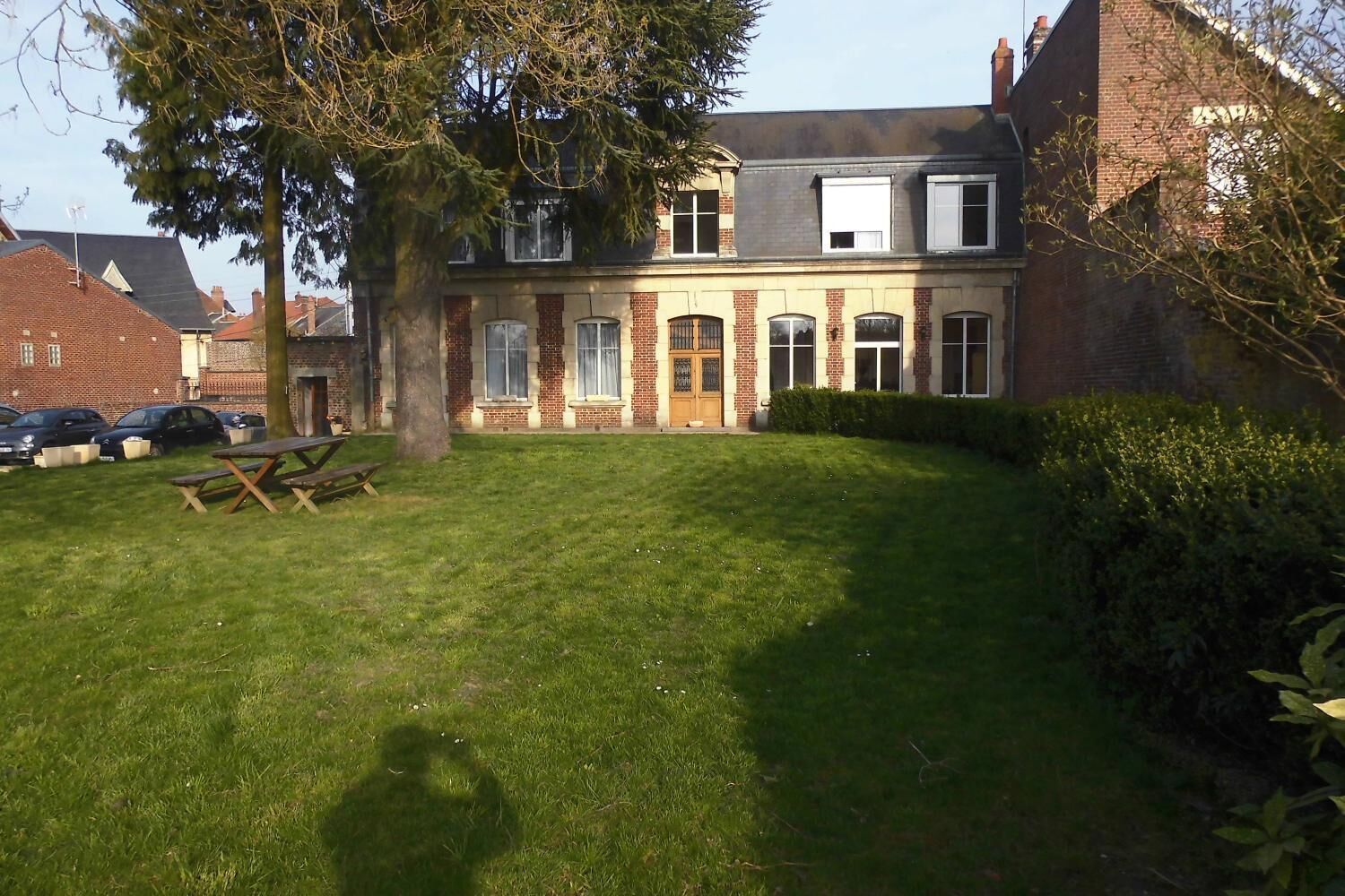 A building with a brick facade, multiple windows, and a grassy lawn.