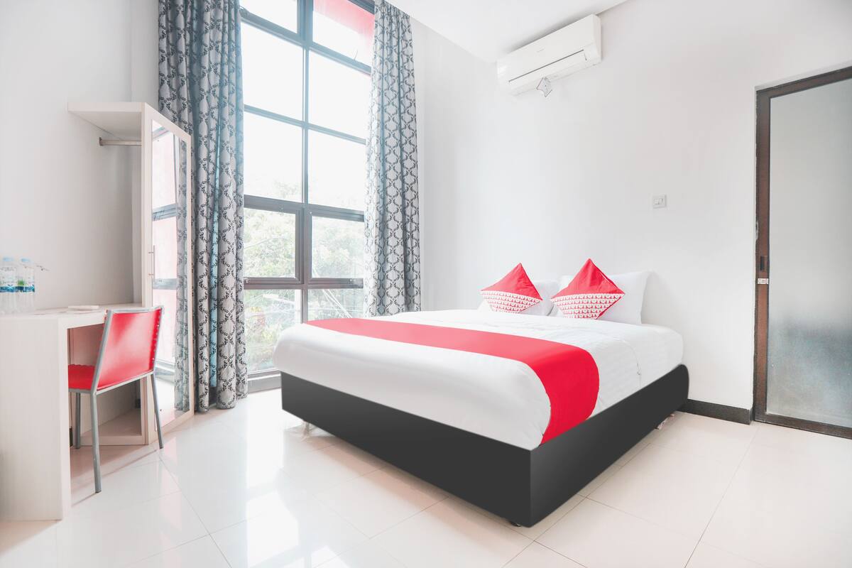 A modern hotel room with a bed, a desk, and a chair.