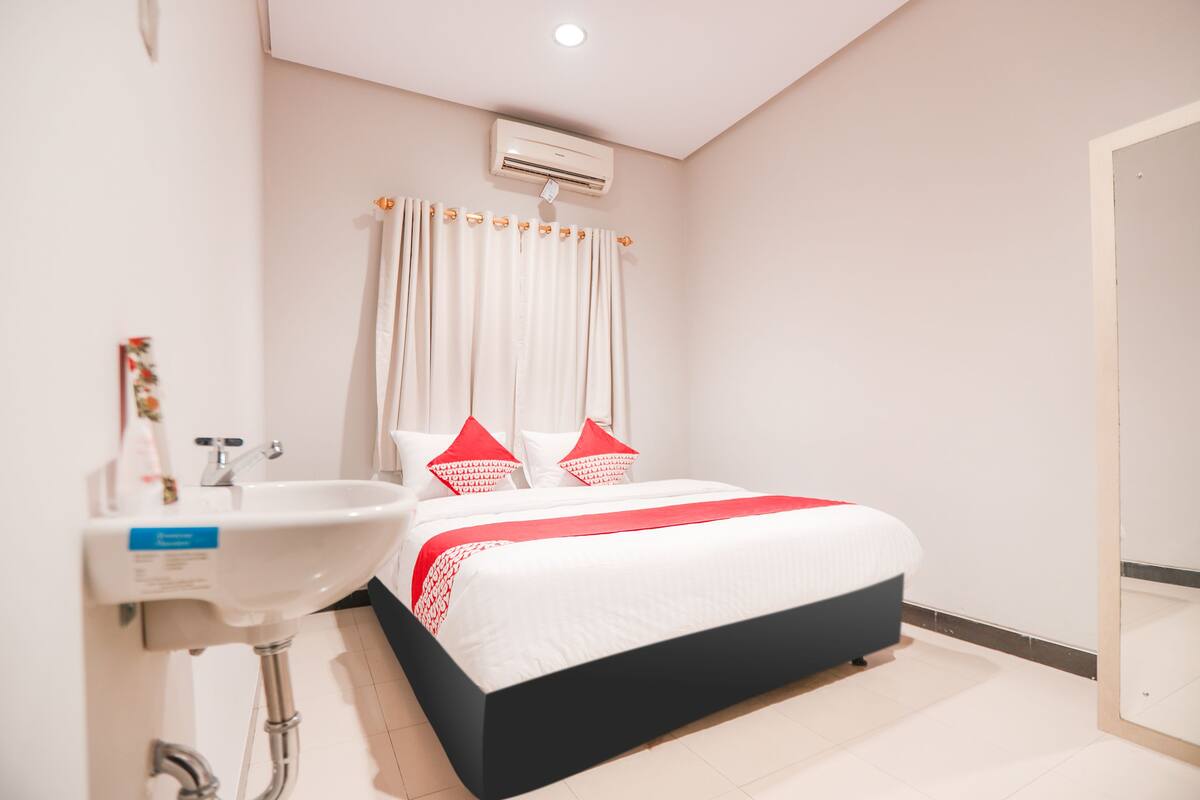 A hotel room with a bed, a sink, and an air conditioning unit.