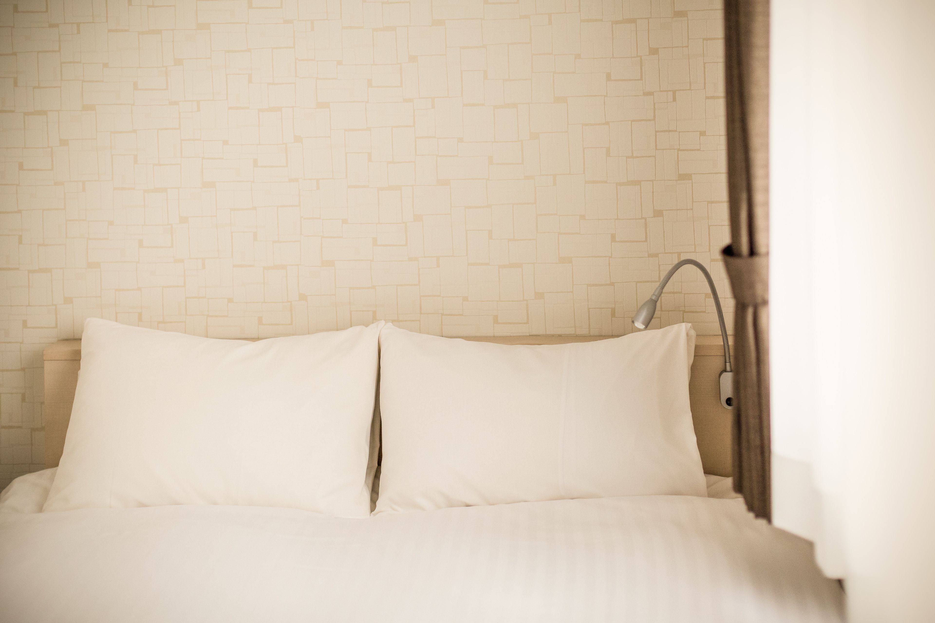 Cama bem arrumada com lençóis brancos e cabeceira moderna.