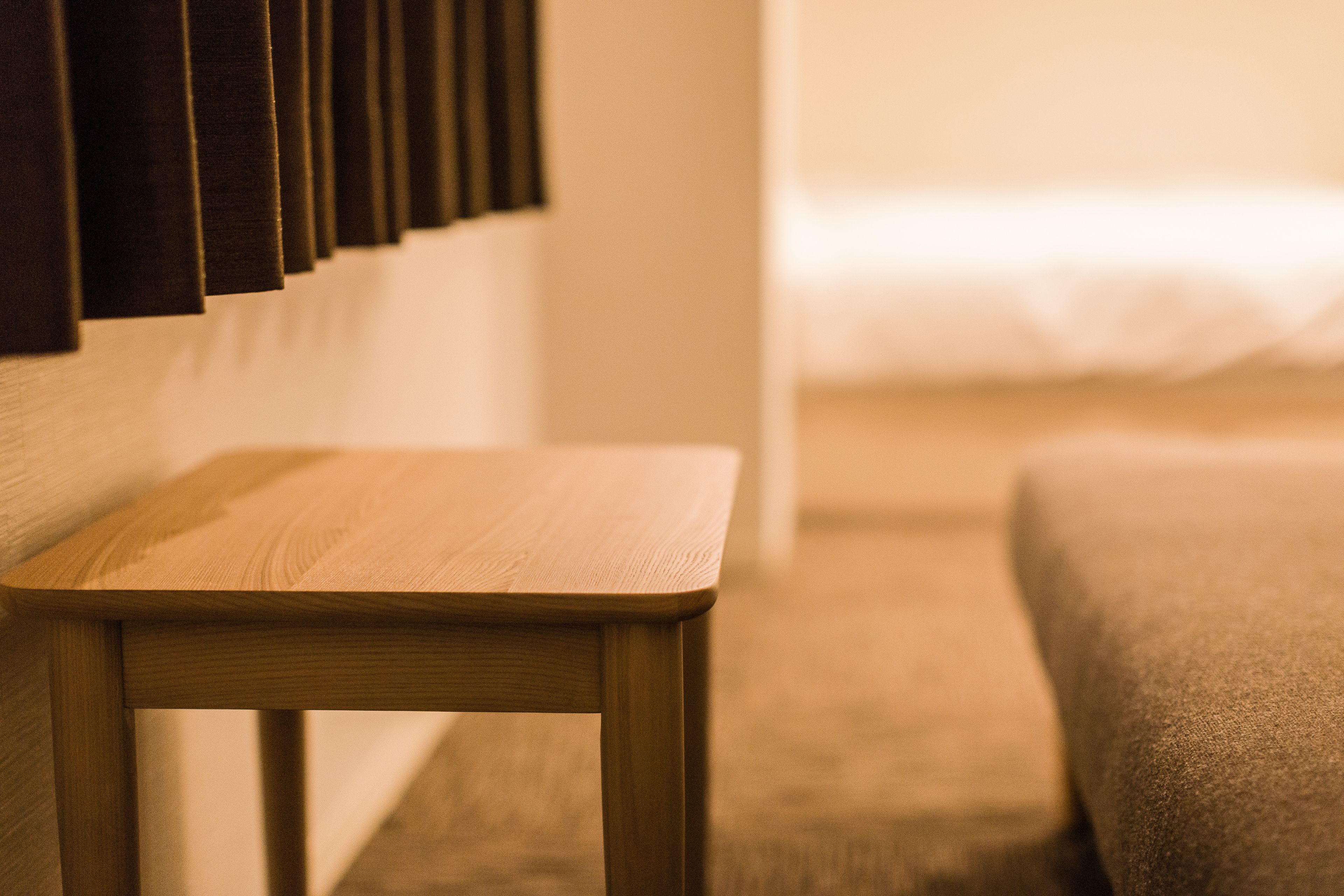 Une table en bois dans une chambre d’hôtel, avec un lit en arrière-plan.