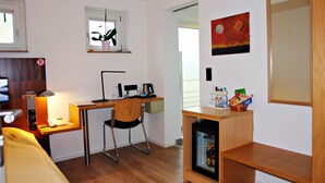Une pièce de taille modeste, équipée d’un bureau, d’une chaise et d’un petit réfrigérateur.