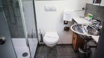 A compact bathroom with a toilet, a sink, and a shower.