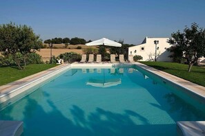 Relax by the pool surrounded by lush greenery and comfortable lounge chairs.