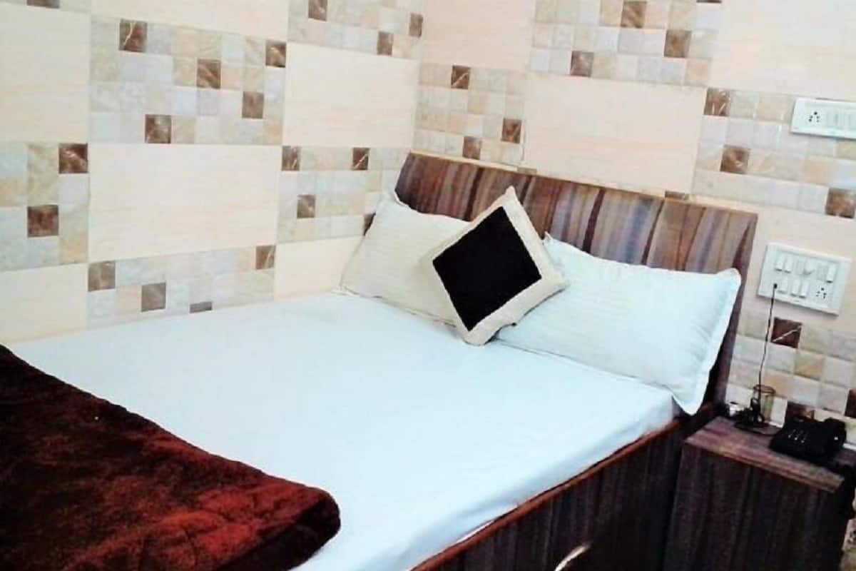 A hotel room with a bed, a wooden headboard, a nightstand, and a wall with patterned tiles.