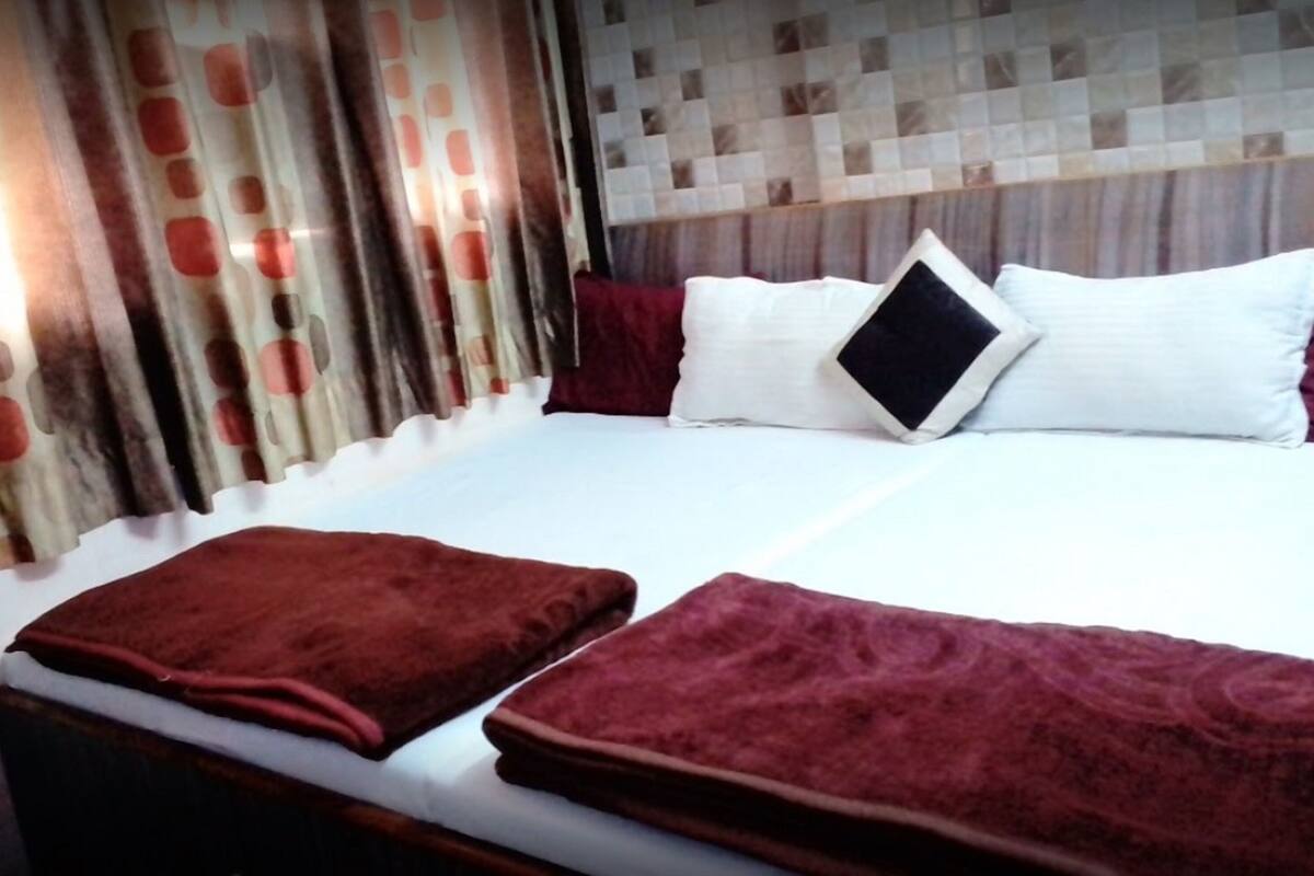 A hotel room with a neatly made bed, a headboard with a patterned design, and curtains with a polka dot pattern.