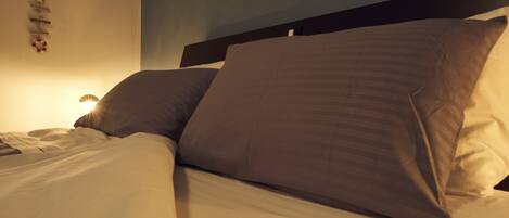 A bed with a headboard, pillows, and a wall-mounted light.