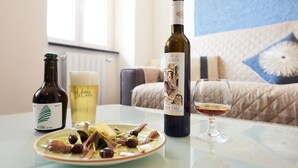 Una mesa de comedor con un plato de comida, una botella de vino y una jarra de cerveza.